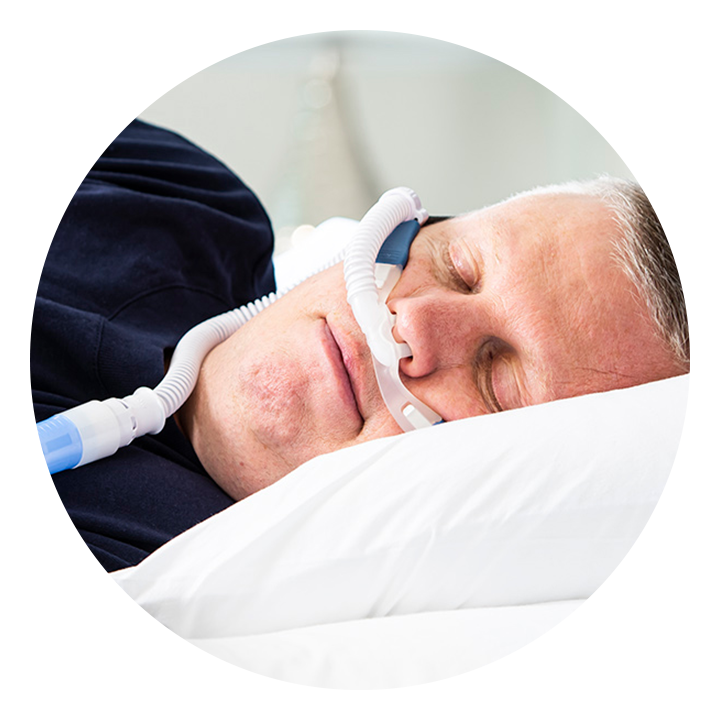 A male patient lies asleep in bed wearing an F&P Optiflow cannula