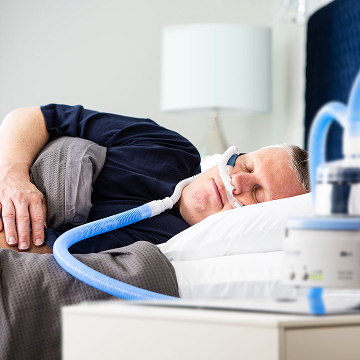 男性患者がF&P 820熱線入り呼吸回路に接続されたネーザルハイフロー (NHF) インターフェースを装着し横向きに眠っている様子